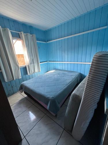 Cette chambre bleue comprend un lit et une fenêtre. dans l'établissement Aluguel casa para temporada, à Itapema