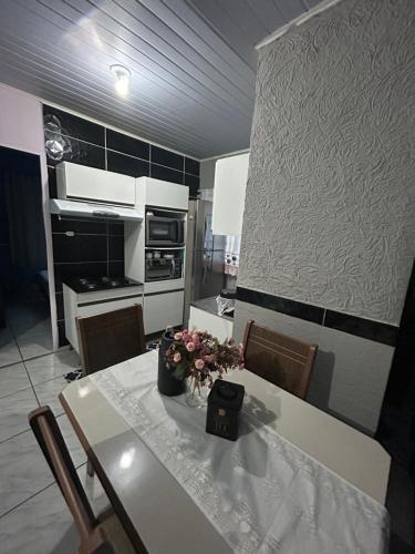 - une cuisine avec une table et des fleurs dans l'établissement Aluguel casa para temporada, à Itapema