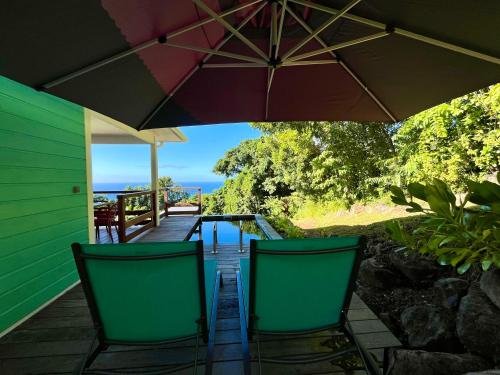 a deck with two chairs and an umbrella at Villa Ti Lagon in Sainte-Luce