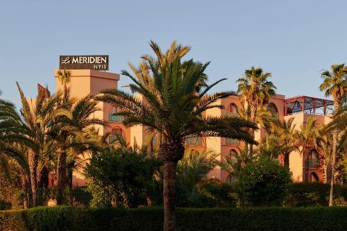 un hotel con palmeras frente a un edificio en Le Meridien N'fis en Marrakech