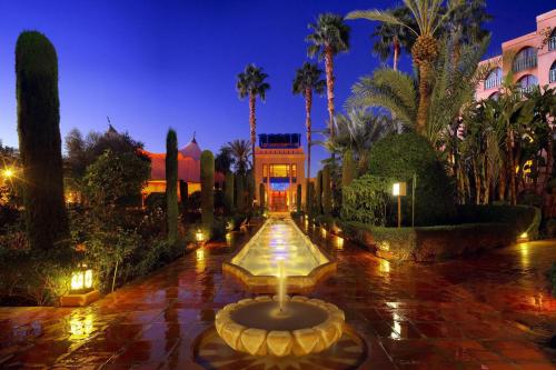 a fountain in the middle of a courtyard with palm trees at Le Meridien N'fis in Marrakesh