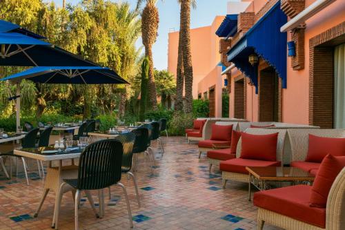 an outdoor patio with chairs and tables and umbrellas at Le Meridien N'fis in Marrakech