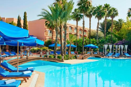 a swimming pool with blue chairs and umbrellas at Le Meridien N'fis in Marrakech