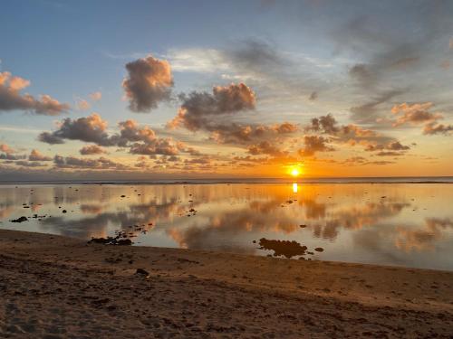 - un coucher de soleil sur la plage avec une réflexion dans l'eau dans l'établissement Te Moana Nui Villa 2, à Arorangi