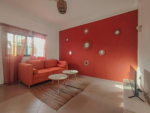 een woonkamer met een bank en een rode muur bij Appartement cosy Cotonou 1 chambre in Cotonou