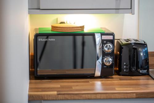 a microwave sitting on a counter next to a toaster oven at Peaceful one bed flat in Stockport centre in Stockport