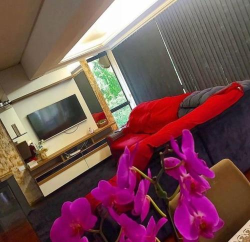 sala de estar con cama roja y flores púrpuras en Pousada Vó Odete, en Lajeado