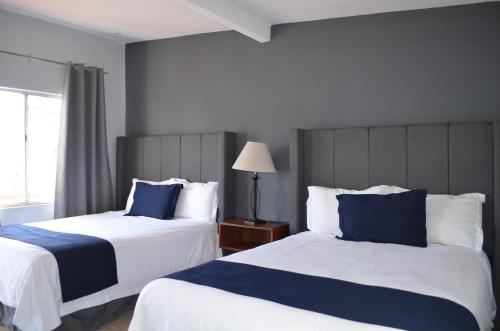 Dos camas en una habitación de hotel con azul y blanco en Hotel CASA PETRI en Ensenada