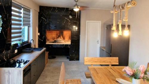 a kitchen with a dining table and a fireplace at Holiday House Above with pool and summer kitchen in Klis