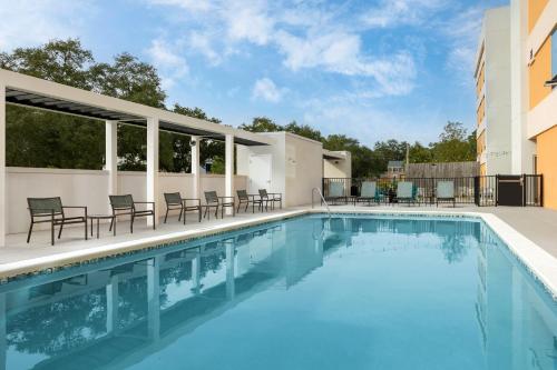 a swimming pool with chairs and tables on a building at Home2 Suites by Hilton Tallahassee State Capitol in Tallahassee