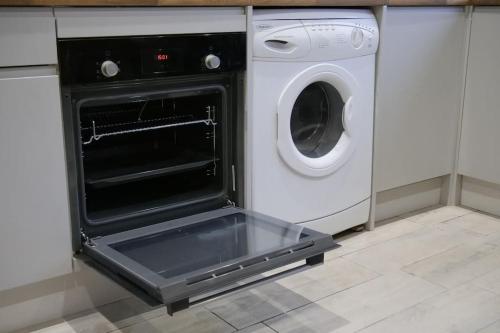 an open oven in a kitchen with a washing machine at The Butcher's Block in Puckeridge