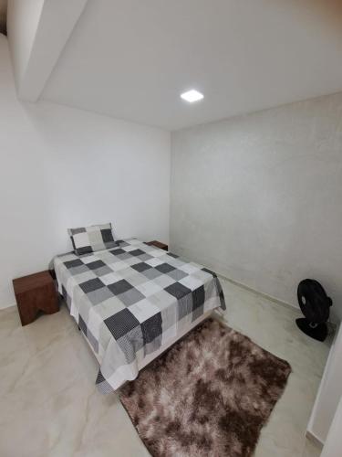 um quarto com uma cama com um cobertor xadrez em Ocker Pousada no Guarujá