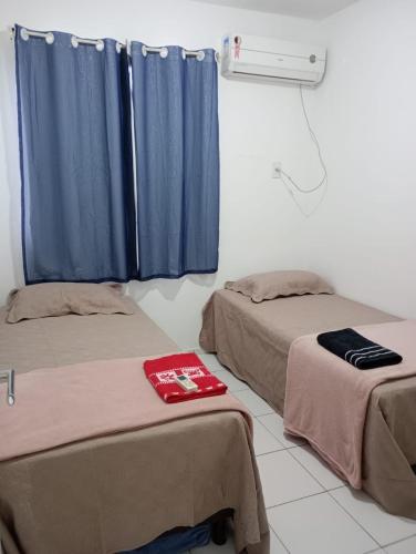 two beds in a room with blue curtains at Apartamento 1 km da praia do aracagir confortavel in São-José-do-Ribamar