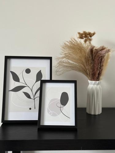 two framed pictures sitting on a table with a vase at Timber Court - FREE PARKING - 2 Bedroom Apartment - FAST Wi-Fi - Perfect for Contractors! in Stifford