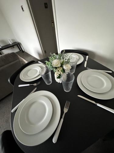 a black table with white plates and utensils on it at Timber Court - 2 free parking spaces - 2 Bedroom Apartment - Fast Wi-Fi - Perfect for Long Term - by Rockman Residences in Stifford