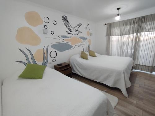 1 dormitorio con 2 camas y un pájaro en la pared en HOSTAL LA MODERNA, en Quintero