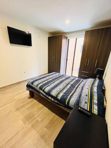 een slaapkamer met een bed en een flatscreen-tv bij Departamento Quinta in San Miguel de Allende