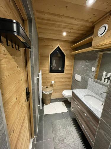 La salle de bains en bois est pourvue de toilettes et d'un lavabo. dans l'établissement Très bel appartement spacieux, aux Carroz d'Arâches