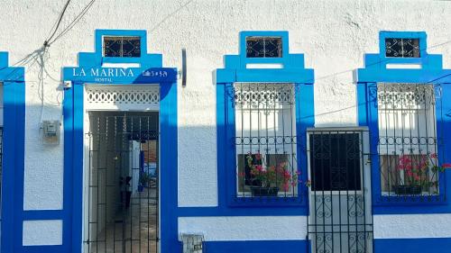 a blue and white building with doors and flowers at La Marina Hostal in Ríohacha