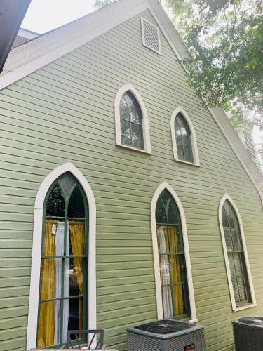 Una iglesia verde con tres ventanas a un lado. en The Downtown Abbey, en San Marcos