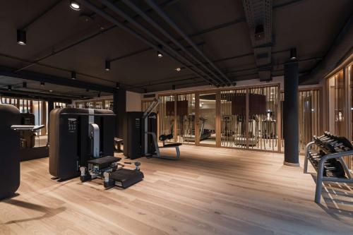 einen Fitnessraum mit Trainingsgeräten in einem Zimmer mit Holzböden in der Unterkunft Infinity Hotel & Conference Resort Munich in Unterschleißheim