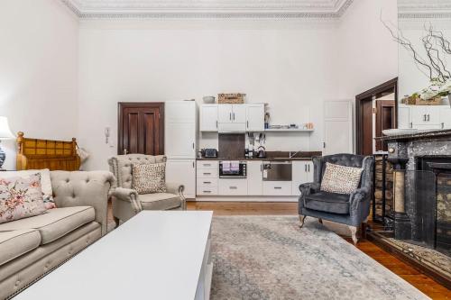 - un salon avec un canapé et une cheminée dans l'établissement Elwood Manor - A Restored Art-Deco Gem, à Melbourne