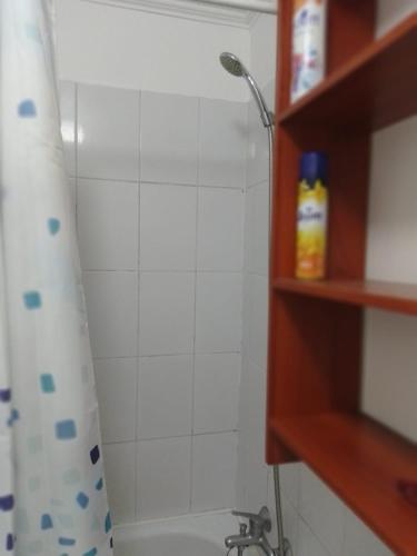 La salle de bains est pourvue d'une douche et d'un mur carrelé blanc. dans l'établissement Departamento en Condominio, à Puerto Montt