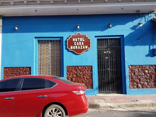 un coche rojo estacionado frente a un edificio azul en HotelCasaMorazanGranadaNicaragua, en Granada