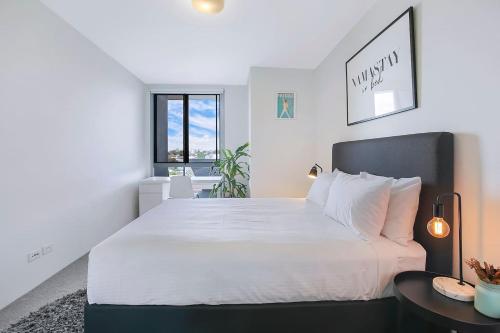 a bedroom with a large white bed and a table at Montague Metropolitan - Brisbane Cityscape Oasis in Brisbane