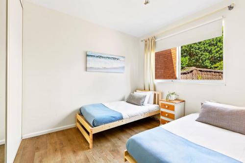 1 dormitorio con 2 camas y ventana en 'Kangaroo Corner' Coastal Charm & Midcentury Flair, en Sídney