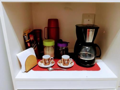 um balcão com duas chávenas de café e uma cafeteira em Cantinho Da Aline 2 em Araçatuba