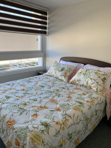 1 dormitorio con 1 cama con edredón de flores y ventana en La Serena se arrienda depto 4p por dia, en La Serena