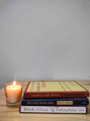 a stack of books with a candle on a table at Hamro Ghar Farmstay in Darjeeling