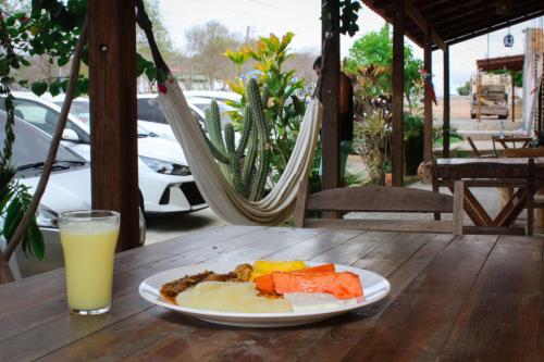 a plate of food on a table with a glass of orange juice at Hotel Mandacaru in Piranhas