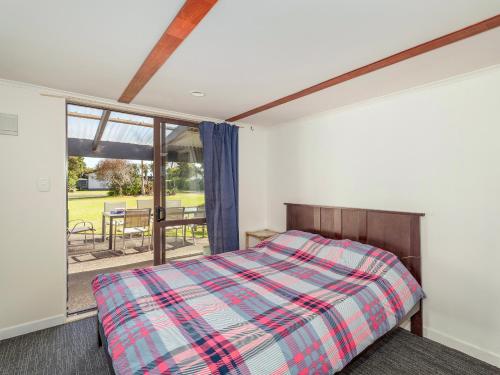 a bedroom with a bed and a large window at Barefoot Daze - Matarangi Holiday Home in Matarangi