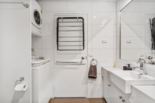 ein weißes Bad mit einem Waschbecken und einer Dusche in der Unterkunft Family Friendly Getaway on Flinders Street in Melbourne