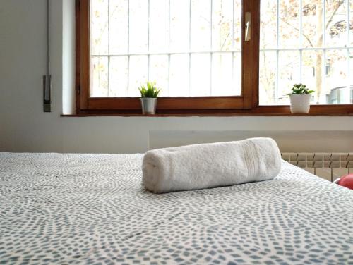 una cama con una toalla delante de una ventana en Habitacion confort en Chamartín en Madrid