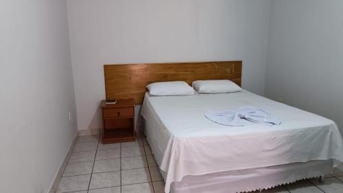 a bedroom with a white bed with a wooden headboard at Hotel Turazzi in Cáceres