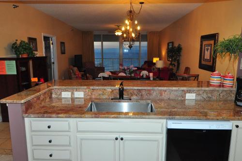 a kitchen counter with a sink and a living room at Beachfront Bliss Absolute Gulf Front 2 Bedroom Condo in Navarre