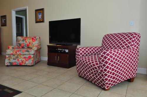 a living room with two chairs and a flat screen tv at Beachfront Bliss Absolute Gulf Front 2 Bedroom Condo in Navarre