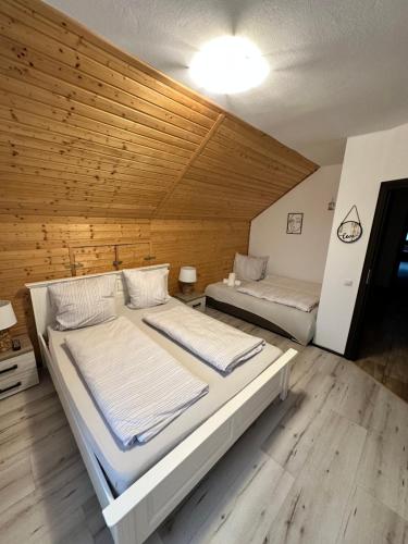 two beds in a room with a wooden wall at Vila Smiley in Avrig