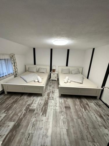 two beds sitting in a room with wooden floors at Smiley Rooms in Avrig