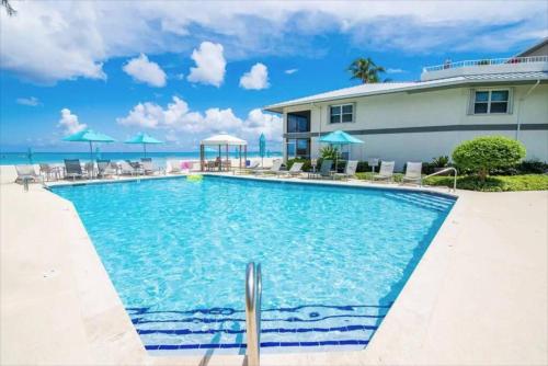 Una piscina en un resort con sillas y sombrillas. en Tamarind Bay Unit # 22, en Dog City