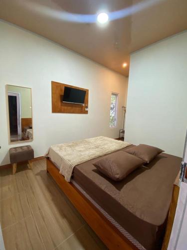a bedroom with a large bed and a tv on the wall at Resy home syariah dekat alun2 wonosobo in Kalianget