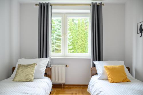 two beds in a room with a window at Bella Casa Premium Apartment - Biesiadna - Warszawa in Warszawa