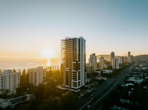 a tall building in a city with the sun setting at Sandbar Burleigh in Gold Coast