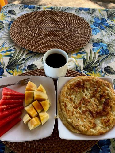 een tafel met een bord eten, een taart en een kop koffie bij Rinjani Beach Eco Resort in Tanjung