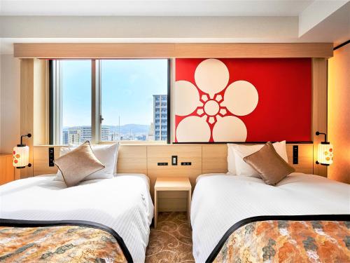 2 camas en una habitación de hotel con una pared roja en Daiwa Roynet Hotel KANAZAWA-MIYABI en Kanazawa