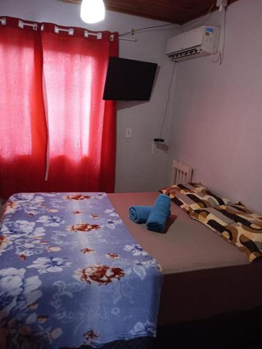 1 dormitorio con cama y cortina roja en Aconchego, en Pântano Grande