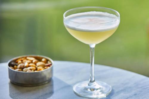 a glass of wine sitting on a table with a bowl of nuts at The Ritz-Carlton, Half Moon Bay in Half Moon Bay
